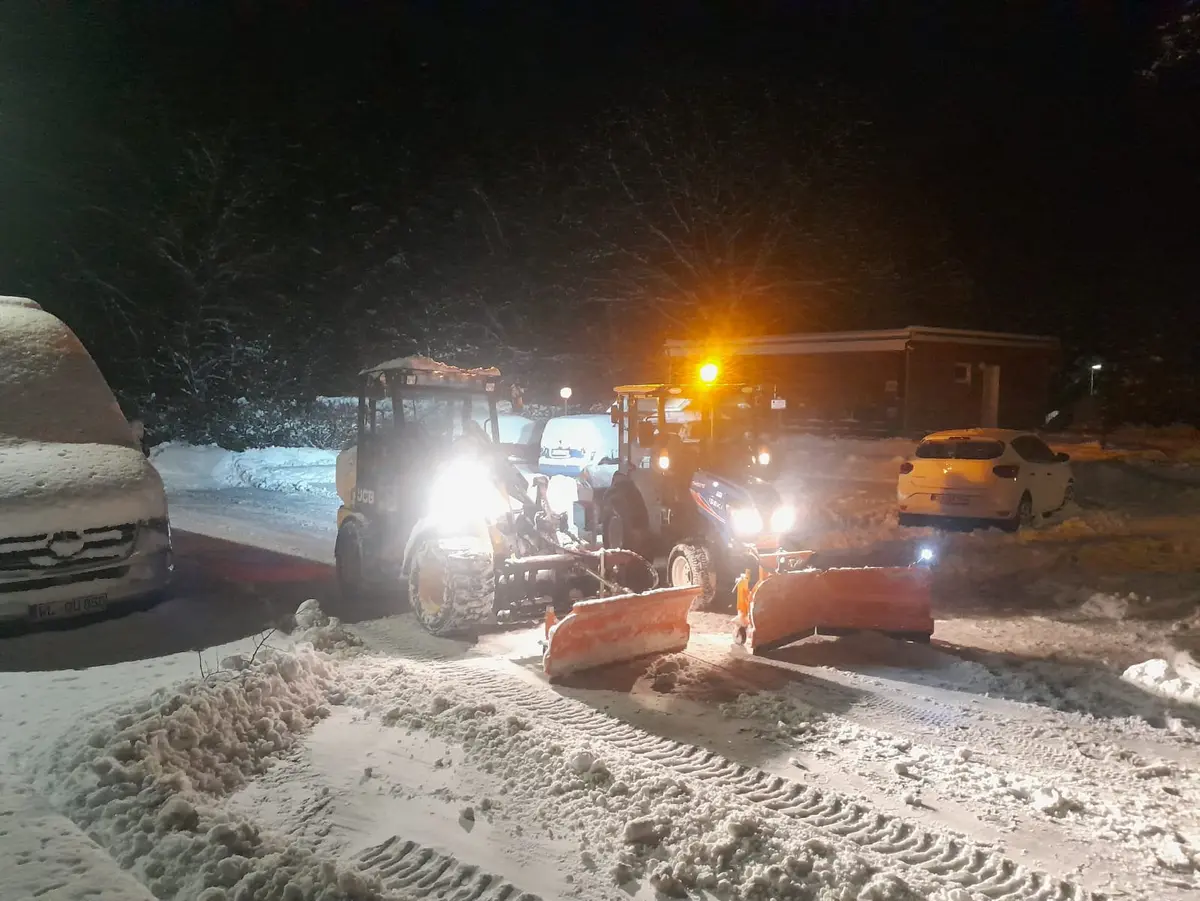 Radlader und Traktor mit Schneepflug bei einem nächtlichen Räumeinsatz